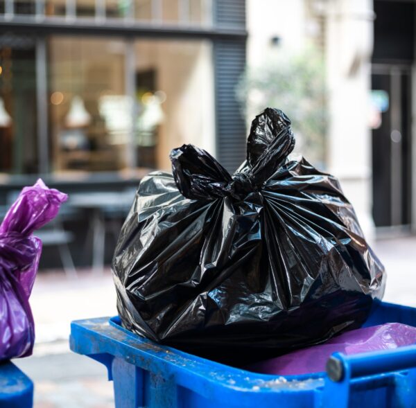 Purple and black bags of trash on a garbage bin during daytime