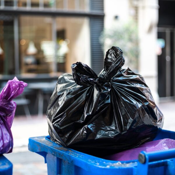Purple and black bags of trash on a garbage bin during daytime
